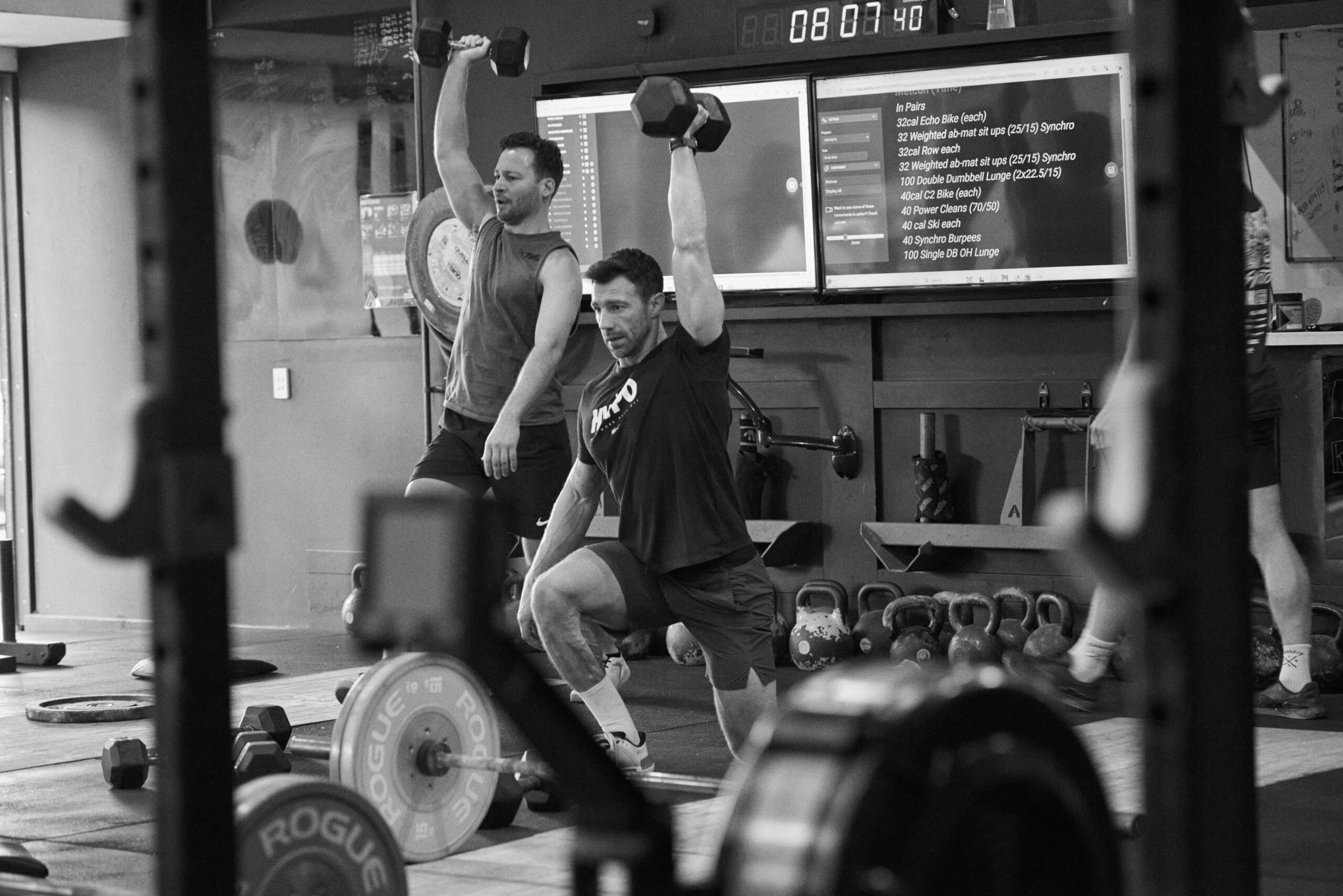 CrossFit Bondi athlete performing an overhead dumbbell movement while learning proper breathing and bracing technique during strength training in Sydney.